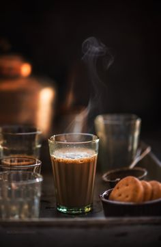 hot chocolate drink with steam rising from the top in front of shot glasses and cookies