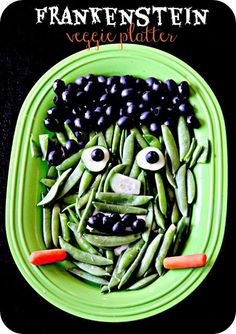 a green plate topped with beans and veggies in the shape of a face