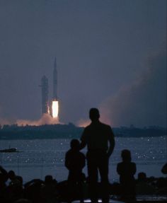 people watch as the space shuttle is launched on its way to the launch pad at night