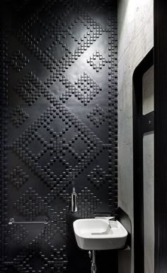 a bathroom with a sink and black tiled walls