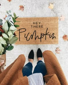 a person standing in front of a door mat that says hey there pumpkin