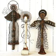 three rusty metal angel sculptures hanging on a white wall