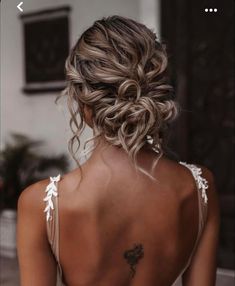 the back of a woman's head with her hair in a low bun and tattoos on it