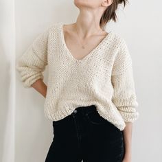 a woman standing in front of a white wall with her hands on her hips and looking up