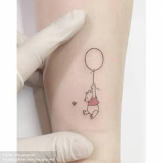 a person with a small tattoo on their arm holding a balloon and flying it in the air