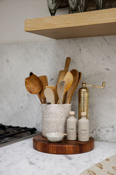 kitchen utensils and wooden spoons in a cup on a marble countertop