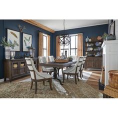 a dining room with blue walls and white chairs in front of a table that is surrounded by other furniture