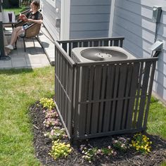 an air conditioner sitting on top of a flower bed in front of a house