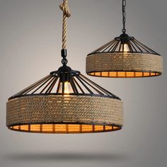 two lamps hanging from the ceiling with rope and lightshades on top of them