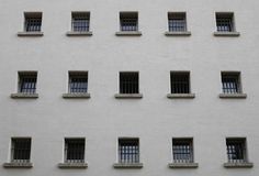 several windows with bars on each side of the window sill in front of a white building