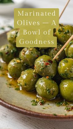 marinated olives in a bowl of goodness with wooden skewers on the side