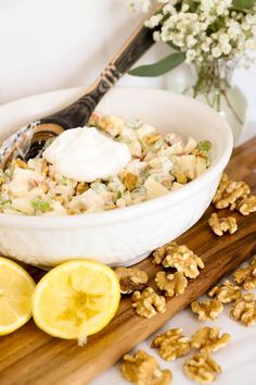 a white bowl filled with granola sitting on top of a cutting board next to sliced lemons