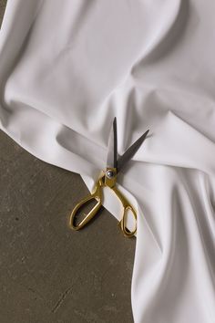 a pair of gold scissors cutting through the white fabric on top of a bed sheet