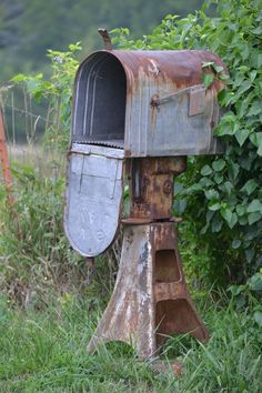 an old rusty mailbox sitting in the grass