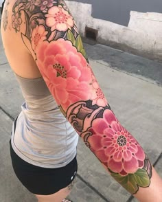 a woman's arm with pink flowers on it and an orange flower in the middle