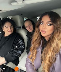 two women sitting in the back seat of a car, one woman is wearing black