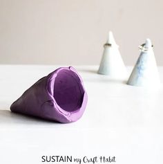 three white and purple vases sitting on top of a table