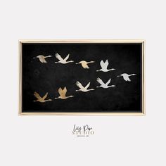 a group of birds flying through the air in a black and gold framed print on a white wall