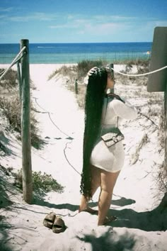 a woman with long hair standing on the beach