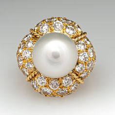 This magnificent cocktail ring is centered with one (1), post set, cultured South Sea pearl. The pearl tops a domed setting is bead set sixty-four (64), bead set, round brilliant cut diamonds. The ring has a split shank design and is accented with seven (7), bead set, round brilliant cut diamonds on each side. The ring measures 21.7mm at the top, rises 18.6mm above the finger, tapering to 2.4mm wide and 1.1mm thick at the base of the shank. The ring is currently size 7. Elegant White Domed Rings, Elegant White Domed Jewelry, Luxury Domed Jewelry For Weddings, Luxury Domed Wedding Jewelry, White Domed Jewelry For Anniversary, Elegant Domed Gemstone Jewelry, Classic Cabochon Pearl Ring For Formal Occasions, White Pearl Ring With 17 Jewels For Formal Occasions, Classic Formal Pearl Ring With Cabochon