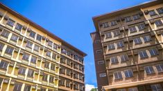 two tall buildings with windows and balconies against a blue sky in the background