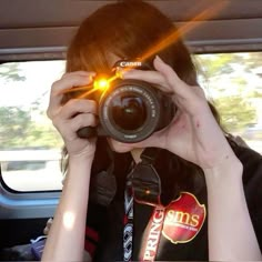 a woman taking a photo in the back seat of a car with her camera up to her face