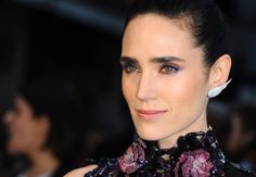 a close up of a person wearing a black dress and flowered necktie with earrings