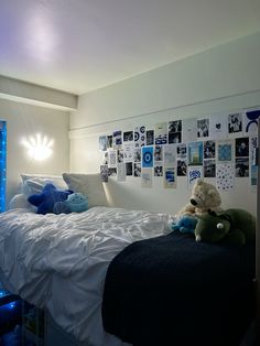 there is a teddy bear sitting on the bed in this room with many pictures on the wall