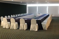 an empty conference room is set up with chairs and table cloths on the tables