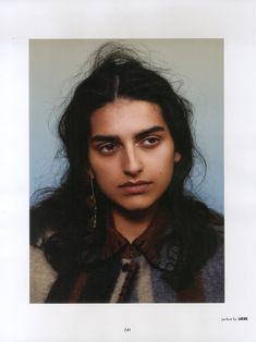 a woman with long black hair and large earrings on her head is looking at the camera