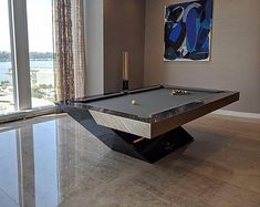 a pool table in the middle of a living room with a large painting on the wall