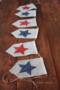 some red, white and blue stars are hanging from string on a wooden table top