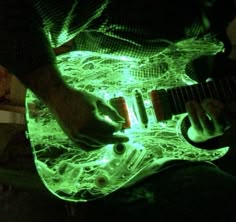 a man is playing an electric guitar in the dark with green light on his body