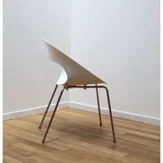 a white chair sitting on top of a hard wood floor next to a white wall