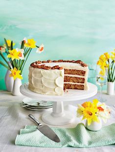 there is a cake with white frosting and yellow flowers on the table next to it