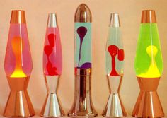 four different colored vases sitting next to each other on a counter top in front of a white wall