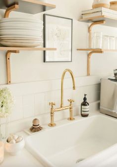 a white kitchen sink sitting next to a shelf filled with plates and bowls on top of it