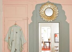 a room with pink walls and an ornate mirror on the wall, along with a coat rack