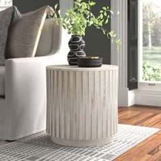 a white couch sitting next to a table with a potted plant on top of it