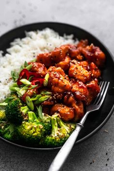 chicken and broccoli served with rice in a black bowl on a gray surface