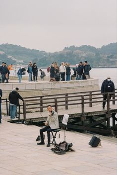 a group of people standing on top of a pier next to the ocean with musical instruments