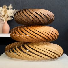 a stack of wooden rings sitting on top of a white table next to a vase