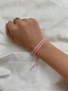 a woman's hand with a bracelet on top of her arm, laying in bed