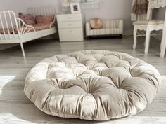 a large round bed sitting on top of a wooden floor next to a white dresser