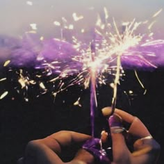 a person holding a purple sparkler in their hand