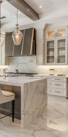 a large kitchen with marble counter tops and white cabinetry, along with two bar stools