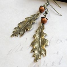 "Here is a lovely pair of oak leaf earrings, comprised of solid brass gold leaf charms, along with copper glass beads, which look like tiny acorns sitting atop the leaves. Earrings come on brass ear wires and are light weight and comfortable to wear. Adorable earrings, perfect for the nature lover! Made in the USA Oak keaf charms measure: 5/8\" x 1.5\" more from my collection here: http://www.etsy.com/shop/botanicalbird About: Botanical Bird is a collection of handcrafted fashion jewelry, both n Leaf Earrings Gold, Oak Leaf Earrings, Oak Leaf Necklace, Earrings Nature, Gold Bar Earrings, Earrings Fall, Gold Leaf Earrings, Cameo Jewelry, Fall Earrings