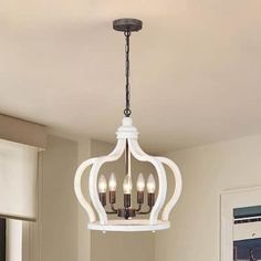 a white chandelier hanging from the ceiling in a dining room with beige walls