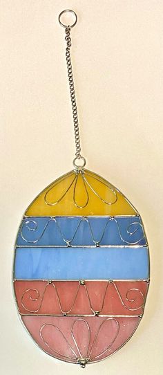 a stained glass sun catcher hanging from a chain on a white wall in a room