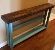 a wooden bench sitting on top of a hard wood floor next to a white wall